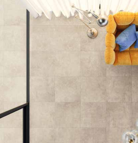 Tuscania Grey Soul 'Sand', beige betonlook vloertegels van bovenaf met een oranje fauteuil en een chromen booglamp