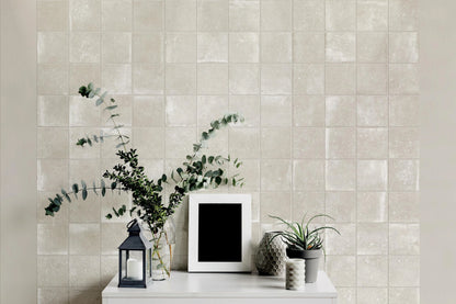 Savoia Italia Heritage 'Sand', crèmekleurige vierkante wandtegels achter een witte console met lantaarn en eucalyptus