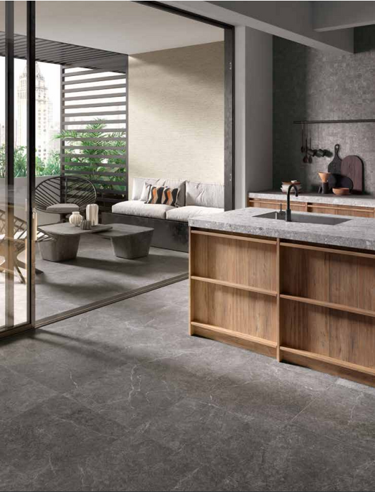Tuscania Holy Stone 'Dark', donkergrijze natuursteenlook vloertegels in een open keuken met kookeiland en zicht op een balkon