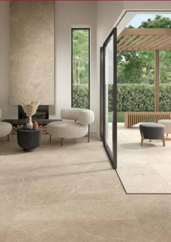 Tuscania Holy Stone 'Beige', beige natuursteenlook vloertegels in een woonkamer die doorloopt naar een terras met pergola