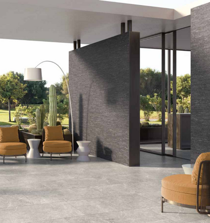 Tuscania Holy Stone 'Grey', grijze natuursteenlook vloertegels in een overdekte veranda met okergele fauteuils