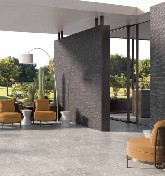 Tuscania Holy Stone 'Grey', grijze natuursteenlook vloertegels in een overdekte veranda met okergele fauteuils