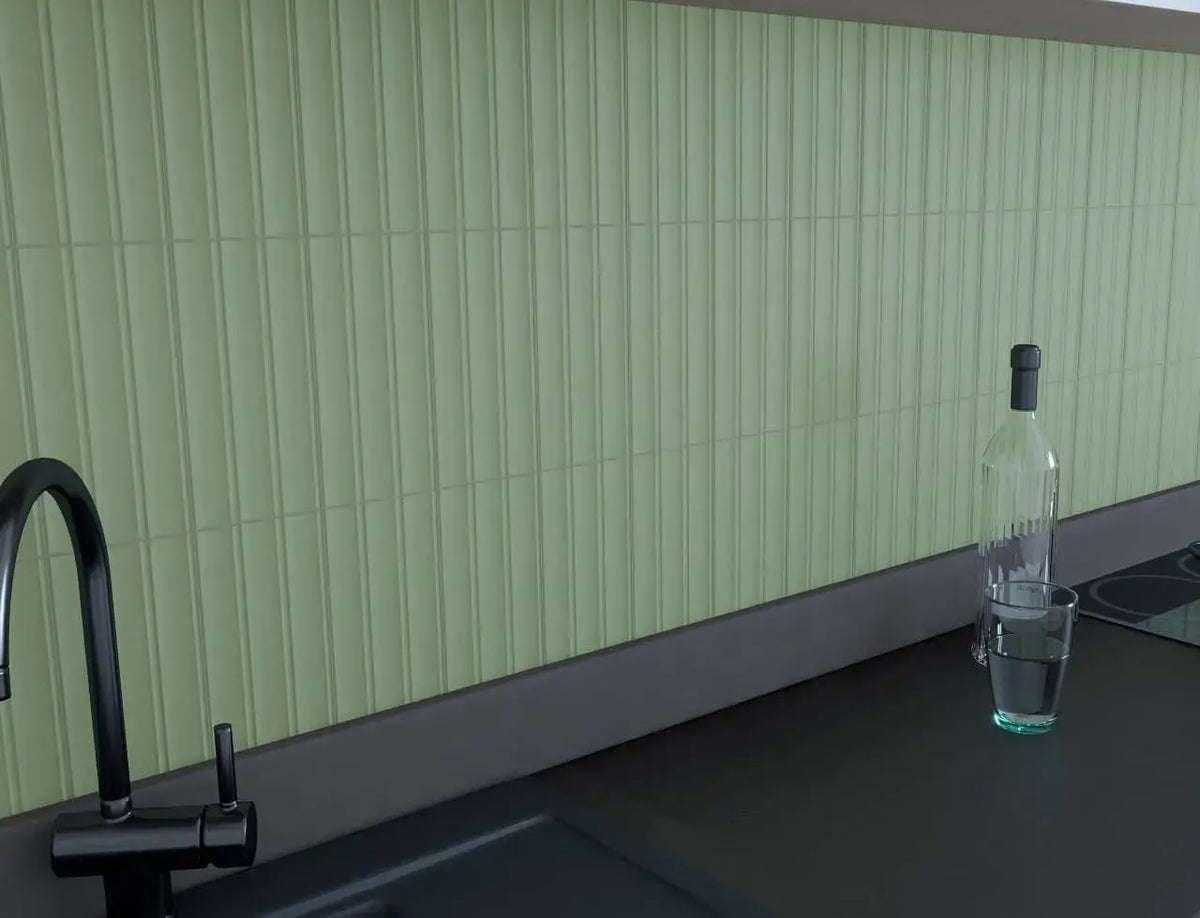 Estudio Cerámico Jaipur 'Celadon', lichtgroene geribbelde wandtegels als keukenachterwand met zwarte kraan en glazen fles