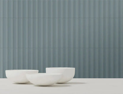 Estudio Cerámico Jaipur 'Scuba Blue', grijsblauwe wandtegels met verticaal ribbelreliëf, met drie witte schalen ervoor