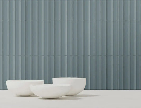 Estudio Cerámico Jaipur 'Scuba Blue', grijsblauwe wandtegels met verticaal ribbelreliëf, met drie witte schalen ervoor