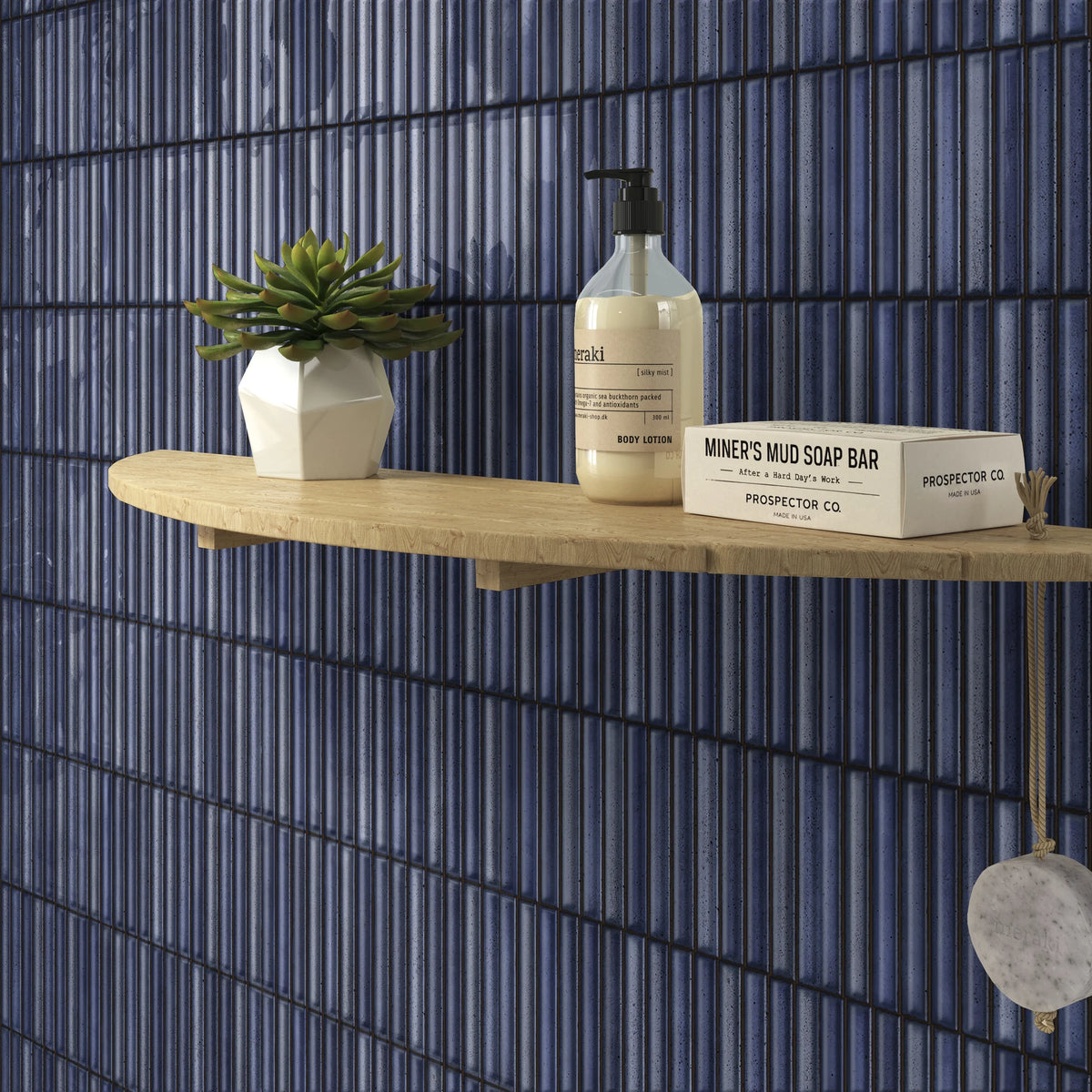 Estudio Cerámico Karatsu 'Midnight', blauwe geribbelde wandtegels achter een houten plank met plant en zeep