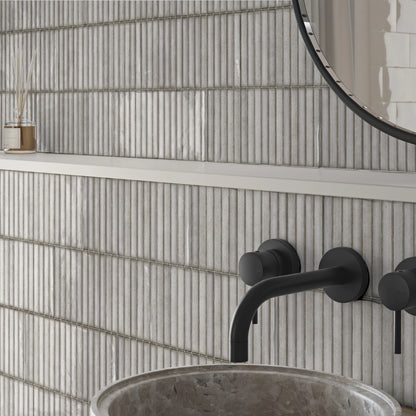 Estudio Cerámico Karatsu 'Chalky', wit-beige geribbelde wandtegels bij een waskom met zwarte kraan en ronde spiegel