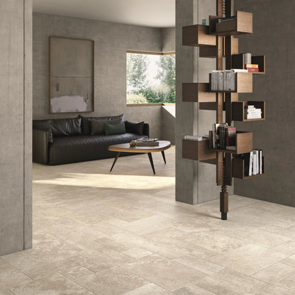 Ceramica Gazzini Lava Stone 'Ivory', beige vloer in een mix van kleinere formaten, woonkamer met leren bank en boekenzuil