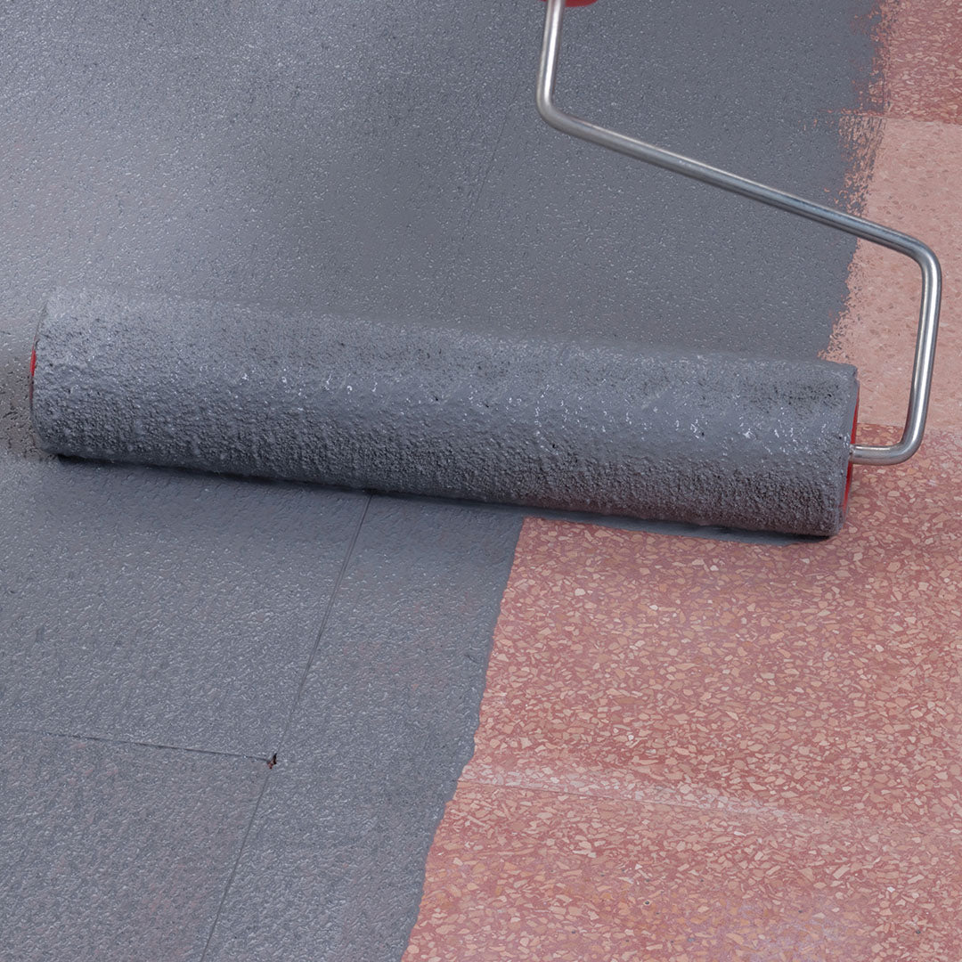 Verfroller die de grijze hechtbrug Eco Prim Grip Plus uitrolt over een rode ondergrond