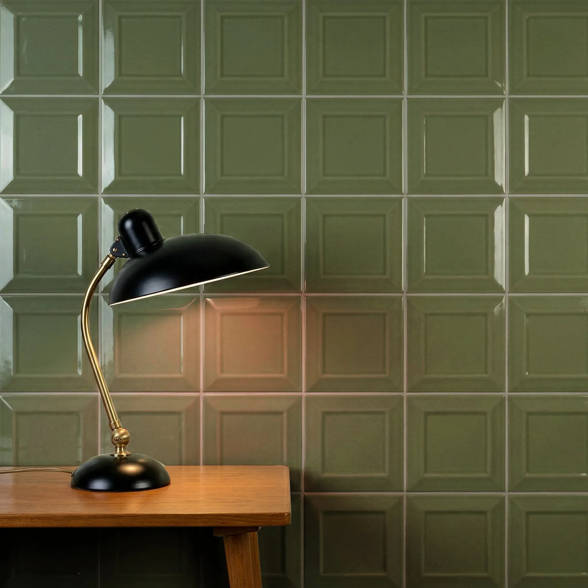 Estudio Cerámico Metropolis 'Vivid Green', olijfgroene wandtegels achter een zwarte bureaulamp op een houten tafel