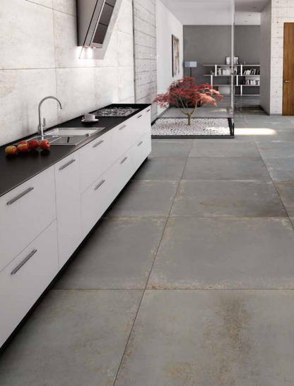 Tuscania Metropolitan 'Iron', grijze betonlook vloertegels in een keuken die doorlopen naar een binnentuin met esdoorn