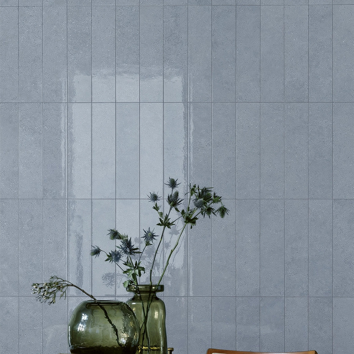 EnergieKer Miro 'Wave Stripe', blauwe tegels, hier als glanzende wandstroken 6x25cm achter een tafel met vazen