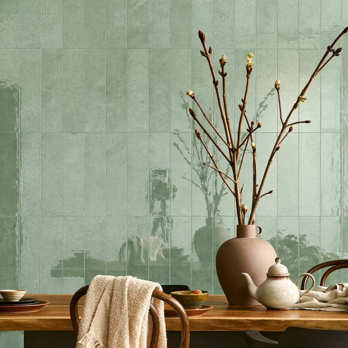EnergieKer Miro 'Basil Stripe', groene tegels, hier als glanzende wandstroken 6x25cm achter een eettafel met takken