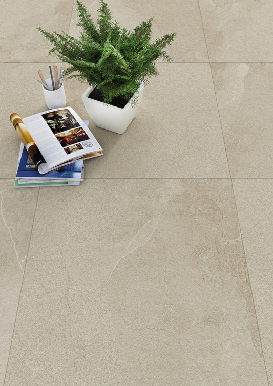 Keraben Mixit 'Beige', beige tegelvloer van bovenaf met een plant in een witte pot, tijdschriften en een fles