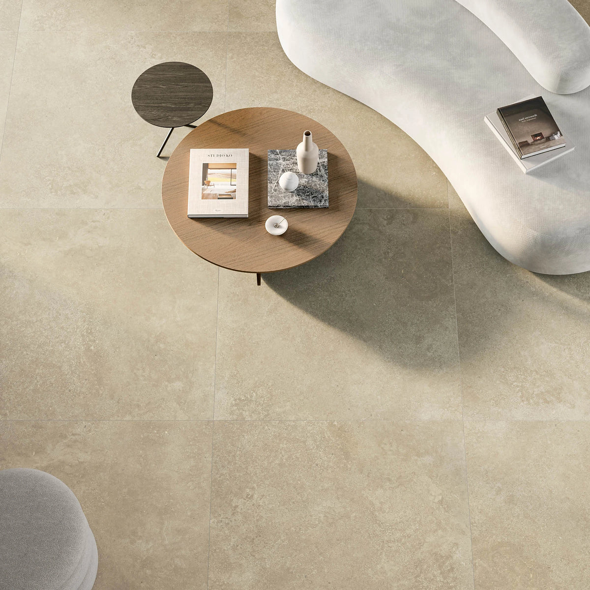 EnergieKer Nereidi 'Ecru Mosaico', hier als beige vloertegels 120x120cm van bovenaf, met witte bank en ronde salontafel