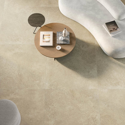 EnergieKer Nereidi 'Ecru', hier als beige vloertegels 120x120cm van bovenaf, met witte bank en ronde salontafel