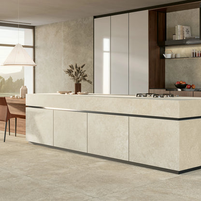 EnergieKer Nereidi 'Umber Muretto', hier als taupe vloer 120x120cm en wand 120x280cm in een keuken met crème kookeiland