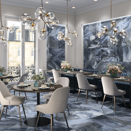 Baldocer Cerámica Nexside 'Blue', grijsblauwe marmerlook wandpanelen in een restaurantzaal met glazen hanglampen