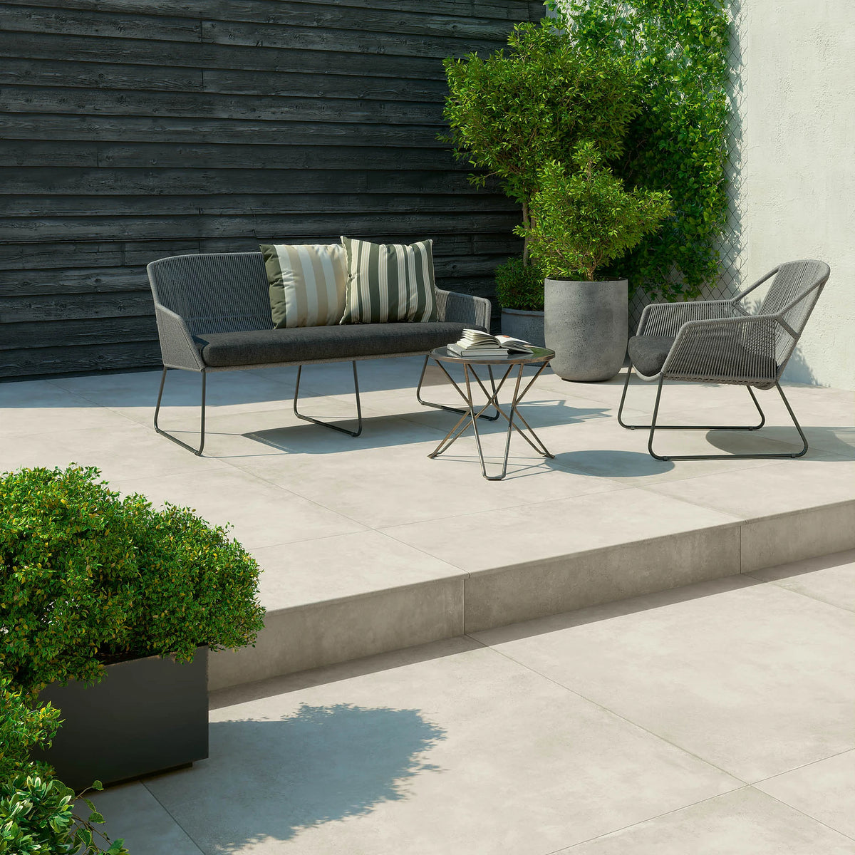 EnergieKer Parker 'White', crèmewitte buitentegels van 2 cm, hier 120x120cm, op een terras met loungeset en zwarte schutting