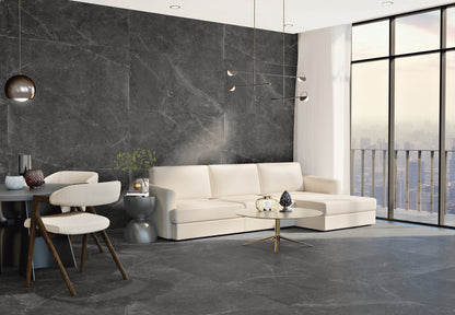 Azulejos Benadresa Pietra Antica 'Nero', antracieten marmerlook tegels in een woonkamer met witte hoekbank en groot raam