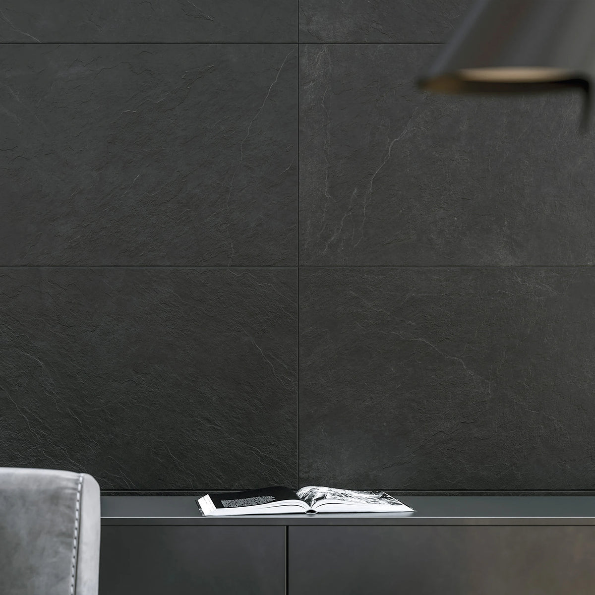 Stargres Pizarra 'Antracite', antraciet leisteenlook wandtegels 60x120cm achter een zwart dressoir met een opengeslagen boek