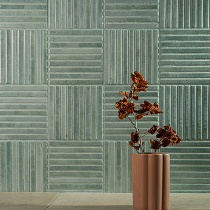 Estudio Cerámico Shallow 'Turquoise', blauwgroene ribbeltegels 14,7x14,7 in blokpatroon met een tak in een terracotta vaas
