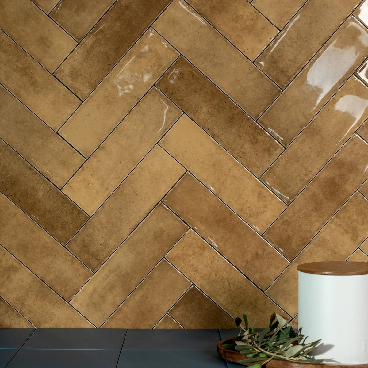 Estudio Cerámico Shallow 'Caramel', bruine glanzende wandtegels 6,4x22,3 in visgraatverband met een witte voorraadpot
