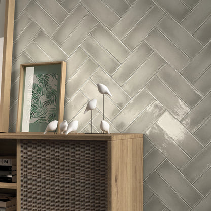 Estudio Cerámico Vermont 'Greige', beige-grijze wandtegels in visgraatverband achter een houten dressoir met vogelbeeldjes