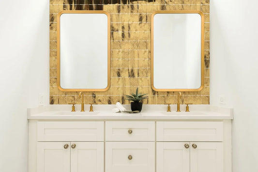 Tebe Vintage 'Gold', goudkleurige glanzende wandtegels achter een wit dubbel wastafelmeubel met twee spiegels