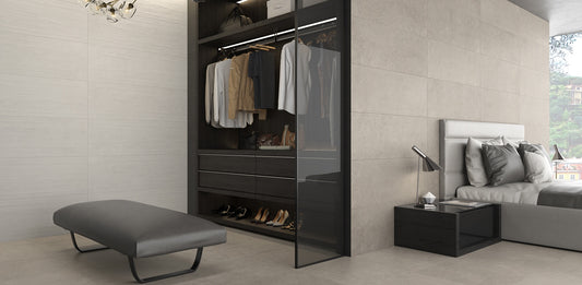 Argenta Cerámica Wave 'Resin Tortora', beige betonlook wandtegels in een slaapkamer met open kledingkast, bankje en bed